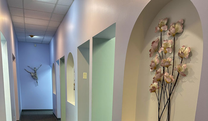 Klavy Usheva, DMD | Dental office hallway with soft lighting, arched doorways, and floral wall dÃ©cor.